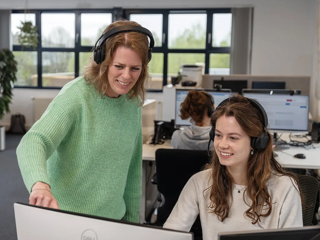 Twee collega's van het MCC hebben overleg met elkaar achter een computer