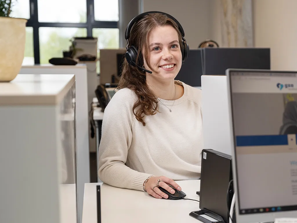 MCC medewerker zit aan de telefoon achter haar computer
